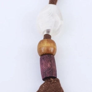 Close-up of linen dress beaded detail with brown braided rope and matte white beads