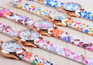 Macro detail of quartz watches with floral silicone straps and rose gold cases on wood