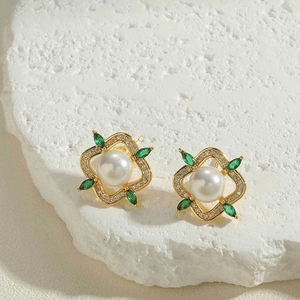 Detailed shot of gold flower earrings with white pearl and green zircon petals