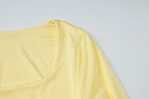 Détail du col en U et de la couture de l'épaule sur une robe en maille jaune
