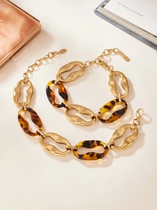 Flat lay of chunky gold stainless steel necklace with leopard resin links on a desk
