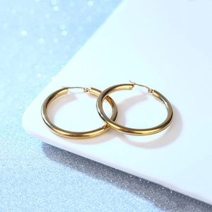 Elegant gold-plated hollow stainless steel hoop earrings on a minimalist white tray