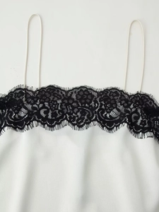 Detailaufnahme des weißen Satintops mit feiner schwarzer Spitze und schmalen Trägern