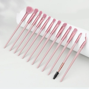 Close-up of 14 professional pink makeup brushes with rose gold ferrules and soft bristles