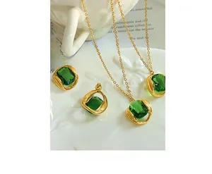 Detail of emerald gemstone pendant and gold chain on vintage white floral porcelain plate