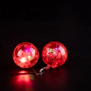 Detail of red glowing LED disco ball earrings with metal hooks on a black background