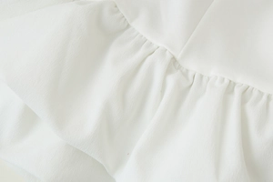 Gros plan détaillé de la texture du tissu mousseline blanc avec volants et coutures