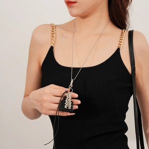 Détail du collier chaîne argenté avec pendentif sac en strass et pompon sur modèle