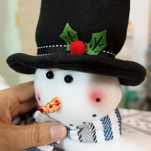 Nahaufnahme eines Schneemann-Vorhanghalters mit schwarzem Hut und blauem Schal