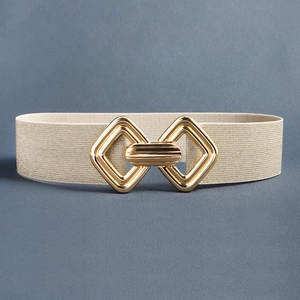 Détail d'une ceinture élastique dorée champagne avec une boucle géométrique entrelacée