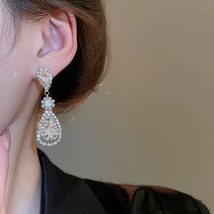Close-up of model wearing vintage gold drop tassel earrings with teardrop crystals