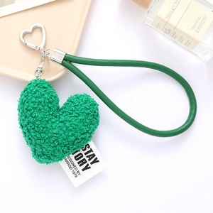 Close-up of a green plush heart keychain with a faux leather strap and metal buckle