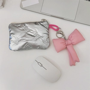 Close-up of quilted silver cosmetic bag with bow embroidery and pink ribbon charm