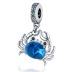 Macro detail of silver crab charm bead with blue gemstone and clear crystals