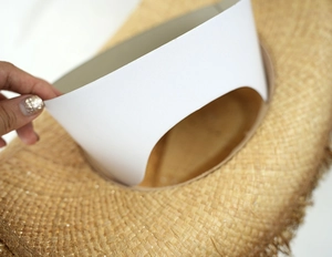 Close-up of natural raffia straw hat weaving detail with inner shaping support