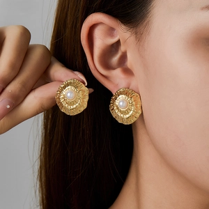 Close-up of a French style gold textured disc earring with a white pearl on the ear