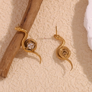 Détail de boucles d'oreilles serpent dorées 18K avec zircon carré sur des branches