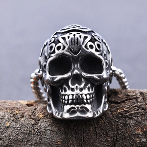 Gothic punk carved skull necklace with an antique silver finish on a dark wood texture