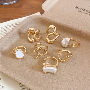 Detailed macro view of gold-plated rings set featuring organic textures and pearl accents