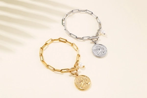 Detail showing gold and silver paperclip bracelets with angel coins and pearl charms