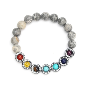 Macro shot of colorful chakra beads and tiger eye stones on a wave-pattern metal charm bracelet