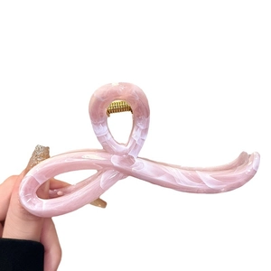 Pink marble texture acrylic hair claw clip with cross bow design shown in hand
