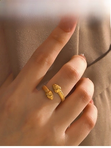 Close-up of golden double-headed snake ring with fine engraved scales and adjustable open design