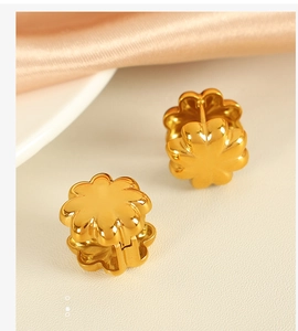 Macro shot of gold floral earrings on champagne satin and beige leather texture