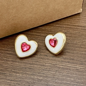 Double layered heart stud earrings with white enamel and red crystal in golden frames