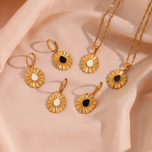 Detail of golden sunburst pendant necklace and earrings on pink satin fabric