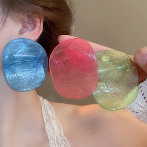 Close-up of oversized translucent acrylic earrings in vibrant blue, pink, and yellow