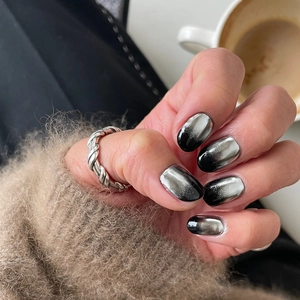 Close-up of black silver gradient cat-eye nails and a silver twisted ring detail
