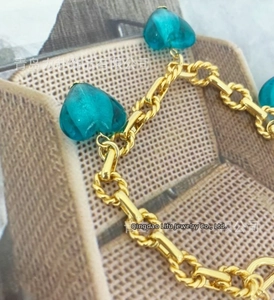 Detail of gold-plated chain bracelet with three blue Murano glass heart charms