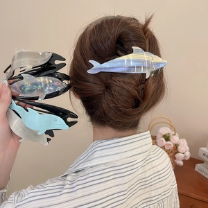 Detailed close-up of glossy dolphin-shaped hair claws with rhinestones and gradient colors