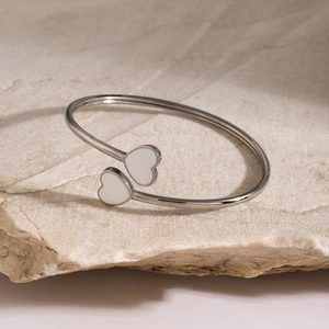 Detailed view of silver open cuff bracelet with white heart-shaped enamel on a stone base