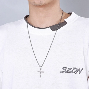 Macro shot of silver textured cross pendant and long metal chain worn by a male model