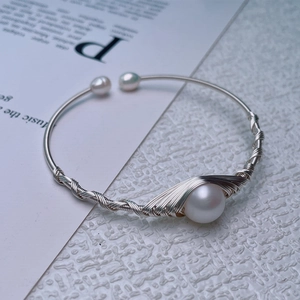 Detailed view of silver wire-wrapped freshwater pearl bracelet on a white textured background
