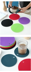 Hands holding a hot pot with honeycomb silicone coasters and stacked colorful mats