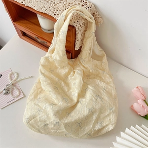 Détail du sac fourre-tout en toile crème avec texture et imprimés de nœuds gris