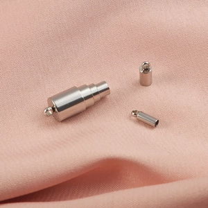 Silver metal magnetic clasp set with end caps for jewelry making on pink fabric