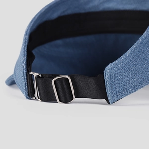 Detail of blue denim sun visor showing adjustable elastic strap and silver metal buckle