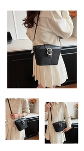 Close-up of black woven shoulder bag with golden round metal buckle and leather strap