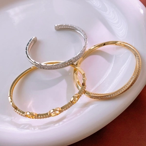 Macro shot of gold and silver plated pave zircon bracelets on white ceramic plate