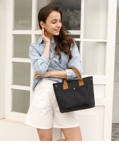 Details of the casual canvas handbag, featuring a sturdy black body and brown handles.