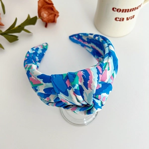 Detailed close-up of blue floral print knotted headband with satin fabric texture