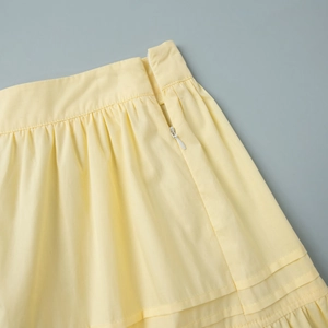 Detail of the pale yellow skirt waist featuring smocked pleats and a matching hidden zipper