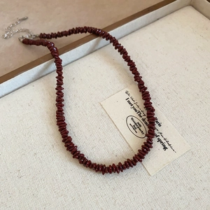 Macro detail of deep red pebble beaded necklace with silver metal extension chain
