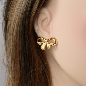 Boucles d'oreilles nœud élégantes en acier inoxydable doré portées par un mannequin