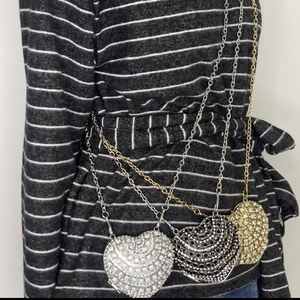 Detailed view of silver, black and gold heart-shaped rhinestone bags with chain straps