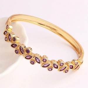 Detailed shot of gold plated bracelet with marquise-cut purple stones on a ceramic plate